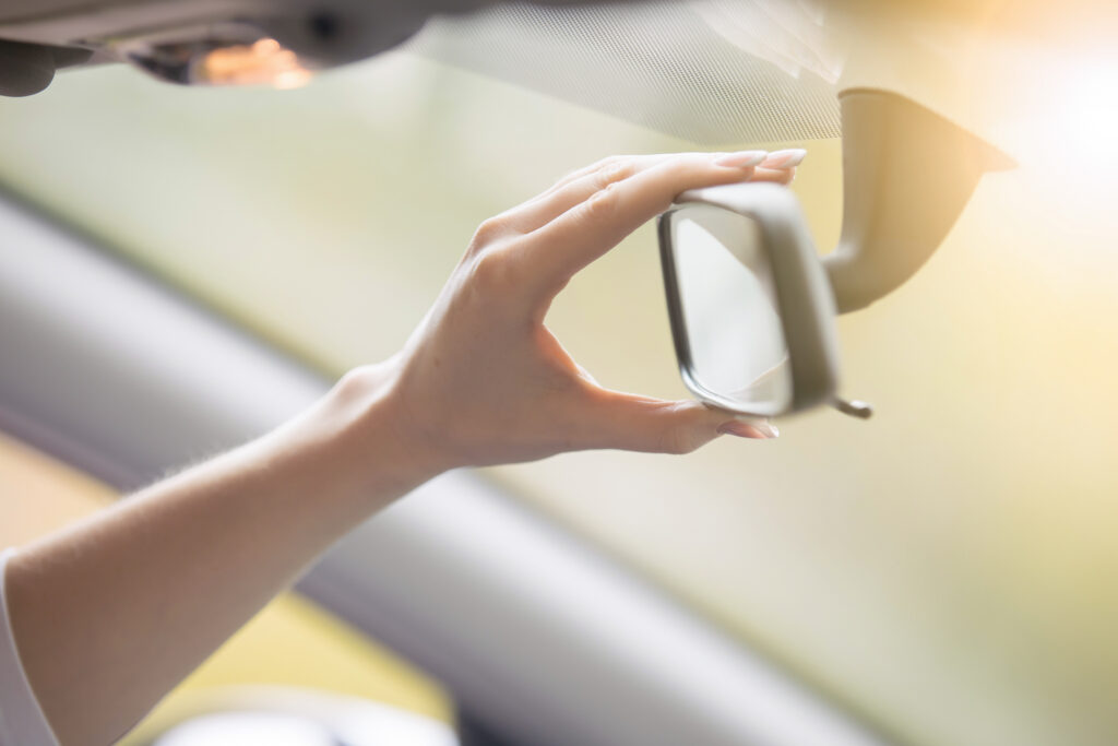 young woman adjusting rear view mirror car