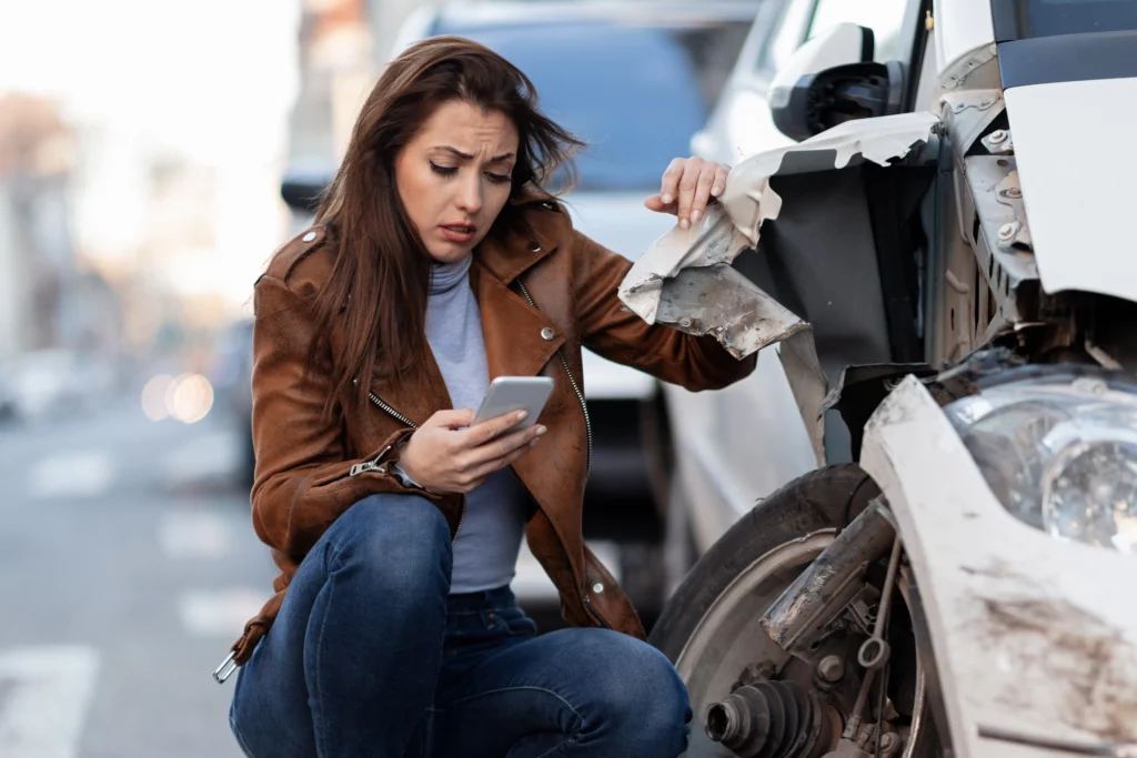 young sad woman text messaging smart after car crash road